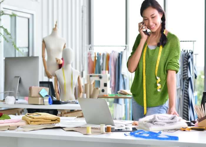 Young Asian woman entrepreneur / fashion designer working in studio Seguros para industria textil